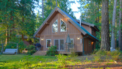 Image of A-frame log cabin surrounded by tall pine trees